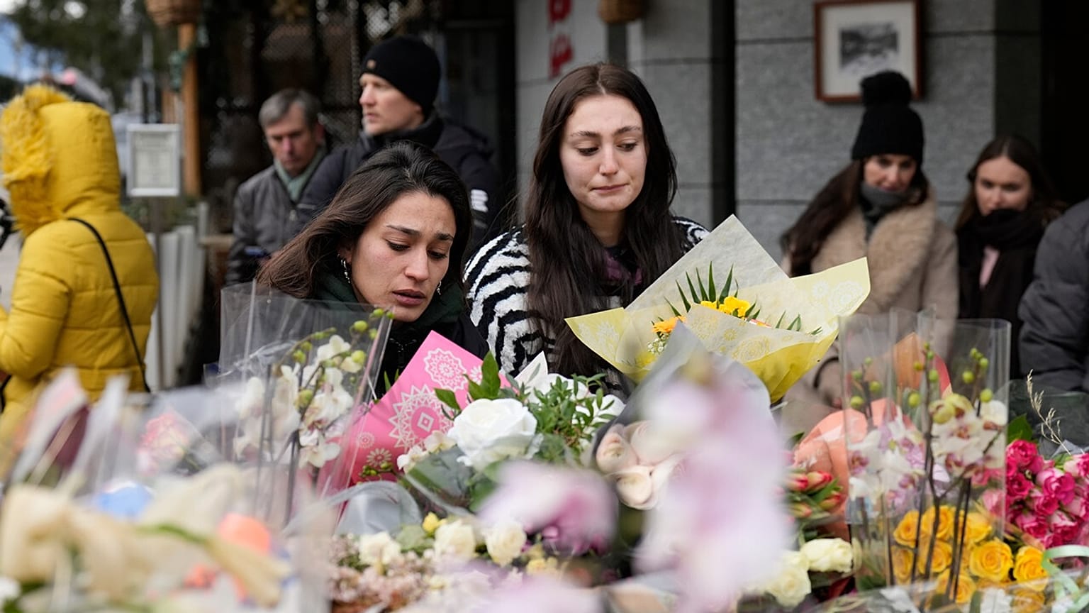 Two women lay flowers near the sealed off Le Constellation bar in Crans-Montana, Swiss Alps, Switzerland, Friday, Jan. 2, 2026.