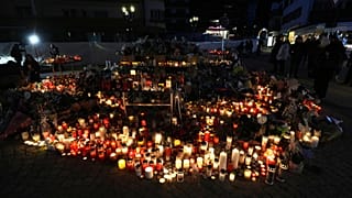 People light candles and place floral tributes outside the sealed off Le Constellation bar in Crans-Montana, Swiss Alps, Switzerland, Sunday, Jan. 4, 2026