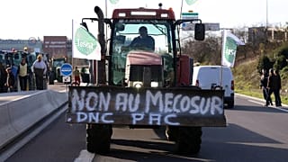 A French farmer drives his tractor to block a main road during a protest against the Mercosur trade deal with South American nations, December 2025