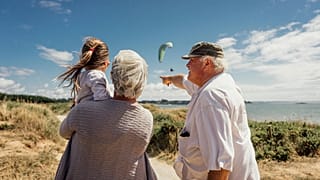 An elderly couple with their granddaughter by the sea