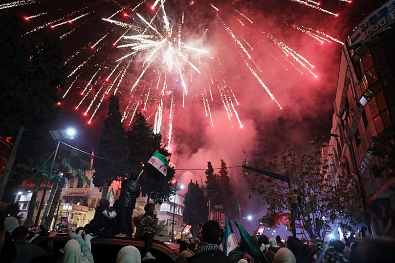 Fireworks illuminate the sky as people fill Clock Square in Homs, 8 December, 2025