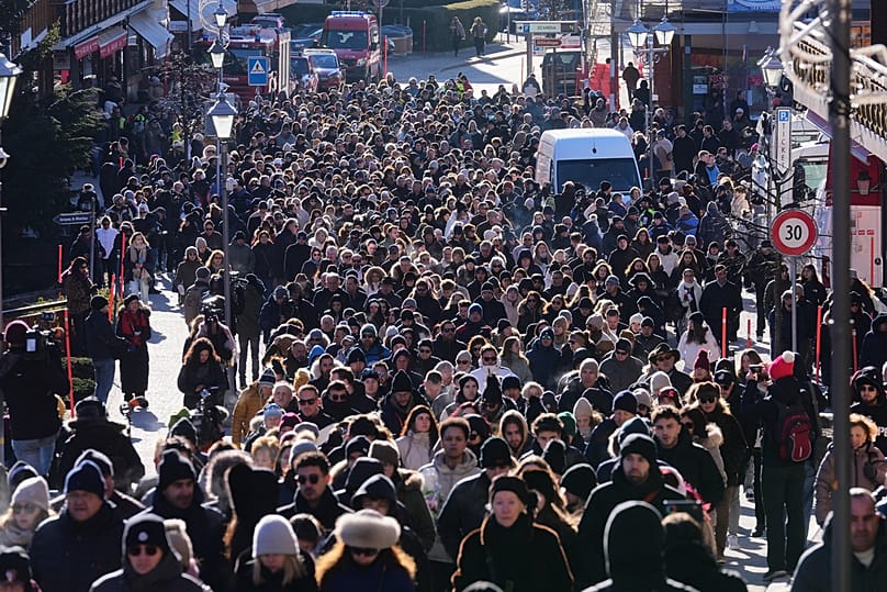 People walk during a memorial procession in Crans-Montana, Swiss Alps, Switzerland, Sunday, Jan. 4, 2026, after a devastating fire in Le Constellation bar.