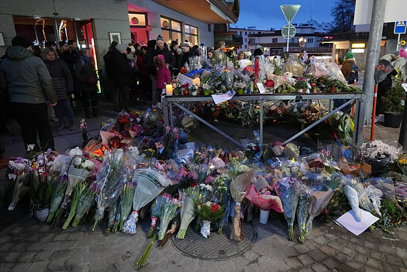 People lay flowers near the sealed off Le Constellation bar in Crans-Montana, Swiss Alps, Switzerland, Friday, Jan. 2, 2026.