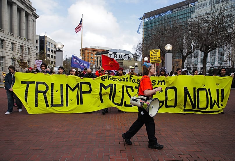 Protestors hold a banner stating "Trump Must Go Now" as they gather during a demonstration against the operation in Venezuela, in San Francisco on Saturday, Jan. 3, 2026