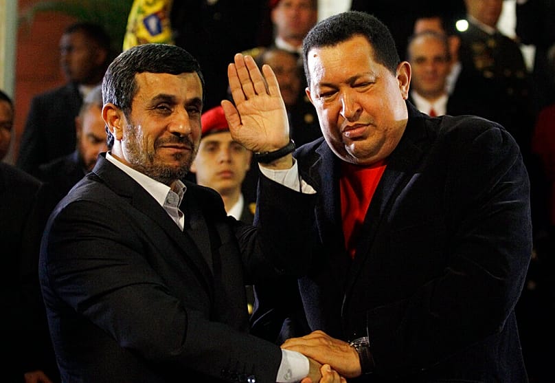 FILE: Iran's President Mahmoud Ahmadinejad waves as he shakes hands with Venezuela's President Hugo Chavez at Miraflores presidential palace in Caracas, 22 June 2012